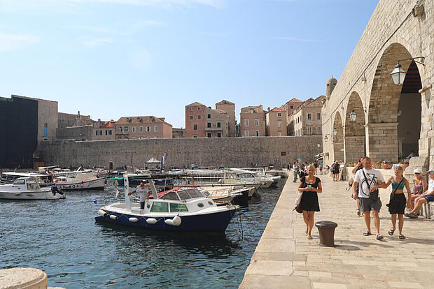 Mesnchen und einige Boote am Hafen von Dubrovnik, Kroatien
